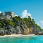 This image shows the stunning ruins of Tulum, where visitors take beautiful photos while enjoying an exclusive private tour. The ancient Mayan structures, with the turquoise Caribbean Sea as a backdrop, create an unforgettable cultural and scenic experience.